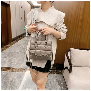 Close-up of a grey quilted square bag with chunky chain detail and adjustable strap