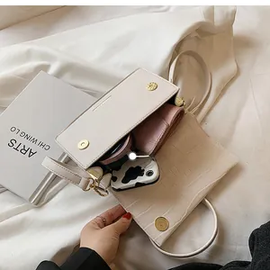 Top view of cream crocodile pattern crossbody bag interior showing daily essentials
