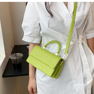 Detail of lime green croc-embossed handbag with twisted handle and golden hardware
