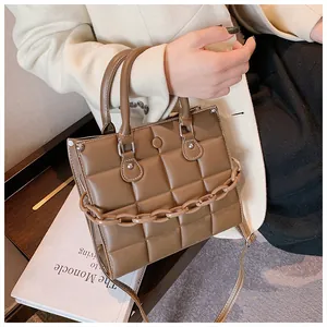 Detail of a brown quilted leather tote bag with thick chain handle and slim shoulder strap