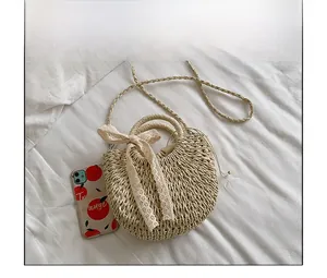 Détail d'un sac en paille tressée beige avec nœud en dentelle et doublure à cordon