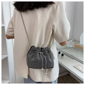 Détail du sac seau noir avec strass, chaîne argentée et perles blanches sur le cordon
