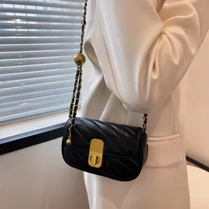 Petit sac matelassé noir avec chaîne dorée et perle porté par un mannequin chic