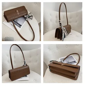 Dettaglio della borsa baguette marrone a stampa coccodrillo con fibbia d'oro e foulard decorativo