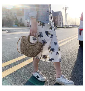Détail du sac à main en paille tressée beige avec poignée ronde et bandoulière au soleil