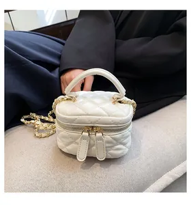 Detail view of white quilted mini vanity bag with gold chain strap and top handle