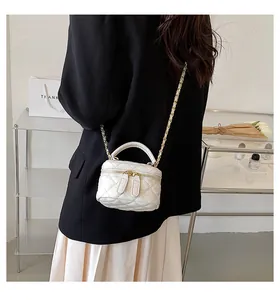 Detailed close-up of a white quilted mini vanity bag with a gold chain strap on a model