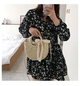 Détail du sac en paille tressé avec nœud en dentelle et cordon de serrage sur robe