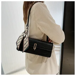 Dettaglio borsa baguette nera motivo coccodrillo con elegante foulard stampa lettere