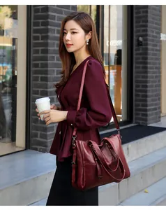 Macro detail of wine red leather shoulder bag showing vertical stitching and texture