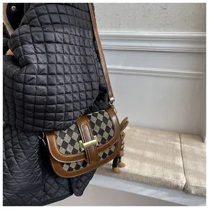 Detalle de bolso bandolera a cuadros marrones con herraje dorado y colgante de conejo