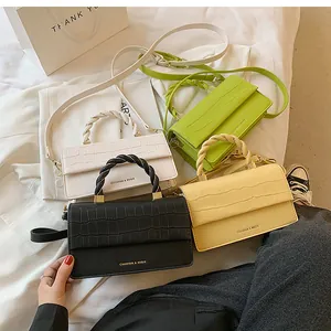 Detailed view of crocodile embossed mini square bags in white, black, green and yellow
