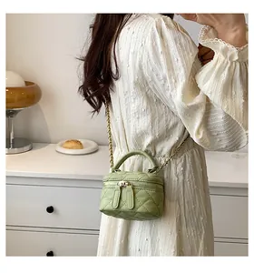 Detail view of light green quilted vanity bag with metal chain strap and leather handle