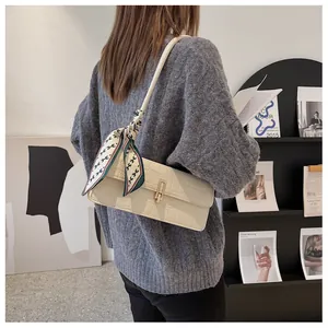 Dettaglio borsa baguette color panna effetto coccodrillo con foulard e fibbia d'oro