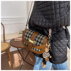 Detalle del bolso de hombro con diseño de pata de gallo, cierre dorado y adorno de conejo
