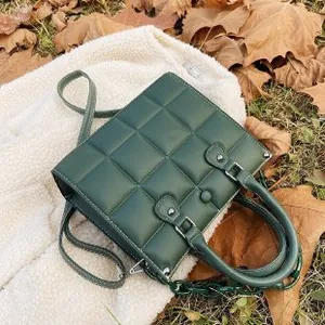 Deep green quilted PU leather handbag with decorative chain and dual straps on white rug