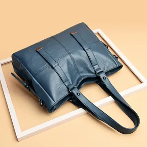 Classic dark blue soft faux leather tote bag with bronze metal buckles on decorative straps