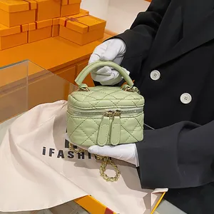 Light green quilted mini box bag with chain strap and top handle on orange gift box