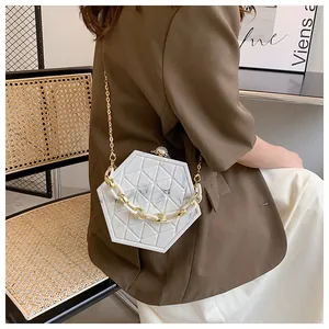 Detail van witte handtas met marmeren textuur, gouden ketting en parelsluiting op model