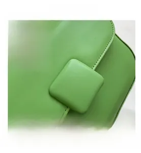 Close-up of grass green leather handbag featuring square buckle and precise stitching