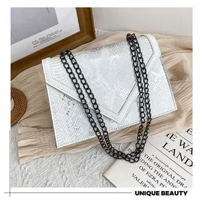 Détail de la texture serpent blanche sur un sac enveloppe classique avec chaîne en métal noir