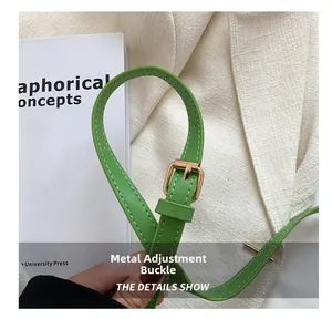 Detail of green leather shoulder strap with golden metal adjustment buckle and stitching