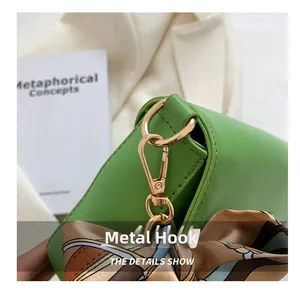 Close-up of high-quality golden metal hook and silk scarf detail on green shoulder bag