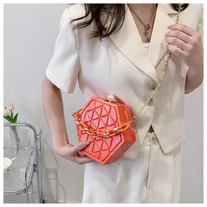 Detail van een feloranje zeshoekige clutch met 3D-textuur en een parelsluiting