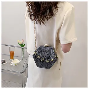 Detail van een zeshoekige clutch met marmerpatroon, parelsluiting en gouden ketting