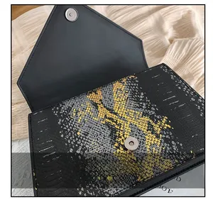 Détail du fermoir magnétique sur le sac à bandoulière enveloppe avec relief de serpent
