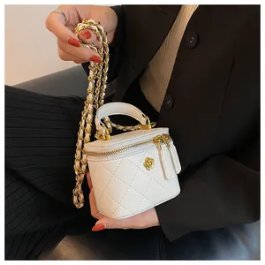 Detail shot of white quilted mini vanity case with gold camellia and chain strap