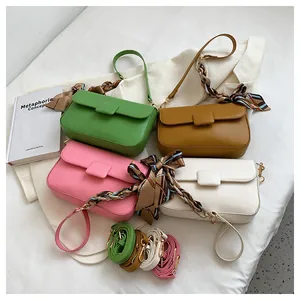 Detail of candy-colored shoulder bags with decorative scarves and metal buckles