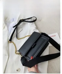 Detail of black crossbody bag with white stitching and stylish metal chain strap