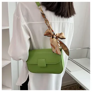 Detail of avocado green crossbody bag with decorative geometric pattern silk scarf strap