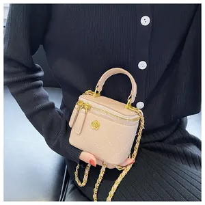 Close-up of pink mini quilted box bag with gold chain and floral metal emblem details