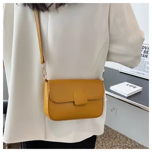 Detail of ginger yellow leather crossbody bag with square buckle and gold metal hardware
