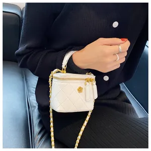 Detail of white quilted mini chain bag with gold camellia ornament and metal handle