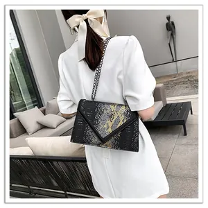 Sac bandoulière chic à motif serpent avec chaîne dorée sur un modèle en robe blanche