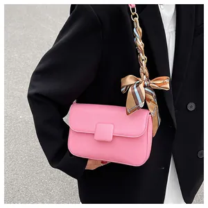 Close-up of pink leather handbag with gold chain strap and elegant floral scarf detail