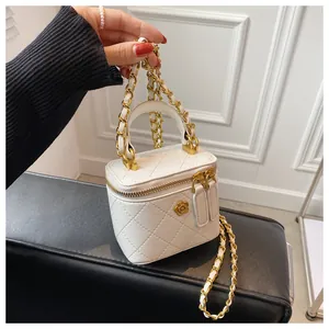 Detail of white quilted mini box bag with gold flower logo and woven chain strap