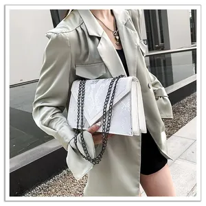 Sac à bandoulière blanc à motif serpent avec chaîne noire sur un costume vert