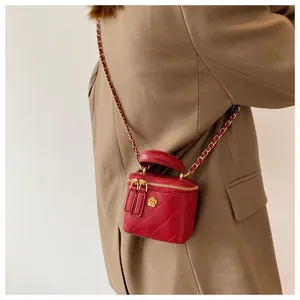 Detail of red quilted mini box bag with gold flower accent and chain strap worn on blazer