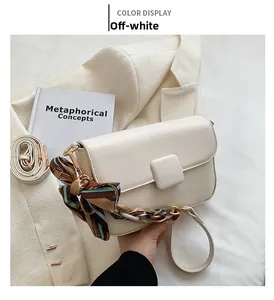 Detail of beige shoulder bag featuring a silk scarf wrapped handle and gold square buckle