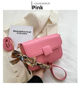 Detailed view of pink shoulder bag with decorative scarf chain and gold hardware