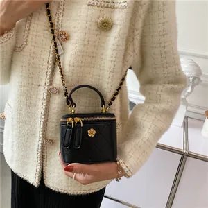 Quilted mini box shoulder bag with gold camellia emblem and chain strap in black