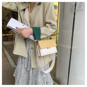 Detail of color-block crossbody bag featuring dual straps and square buckle closure