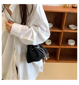 Detail of black rhinestone bucket bag with silver chain strap worn by a model