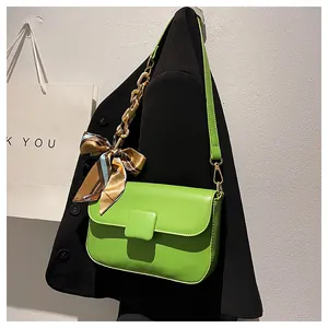 Detail of green PU leather shoulder bag with printed silk scarf chain handle and magnetic flap