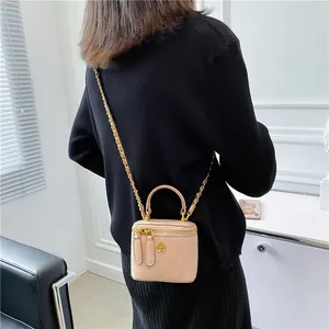 Beige quilted mini box bag with chain strap shown on a model in a minimalist room