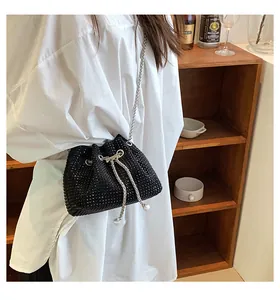 Detail of a black rhinestone bucket bag with pearl drawstrings and silver chain strap